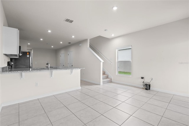 275 Blueberry Ln, Davenport, FL 33837 - kitchen with a peninsula, light stone countertops, a breakfast bar, white cabinets, and recessed lighting