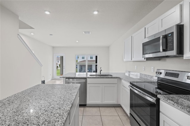 275 Blueberry Ln, Davenport, FL 33837 - kitchen featuring appliances with stainless steel finishes, a peninsula, white cabinets, light stone counters, and recessed lighting