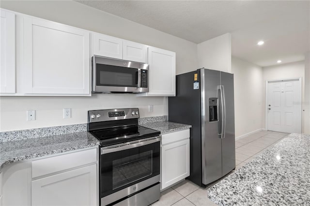 275 Blueberry Ln, Davenport, FL 33837 - kitchen with stainless steel appliances, light tile patterned flooring, white cabinets, light stone counters, and recessed lighting