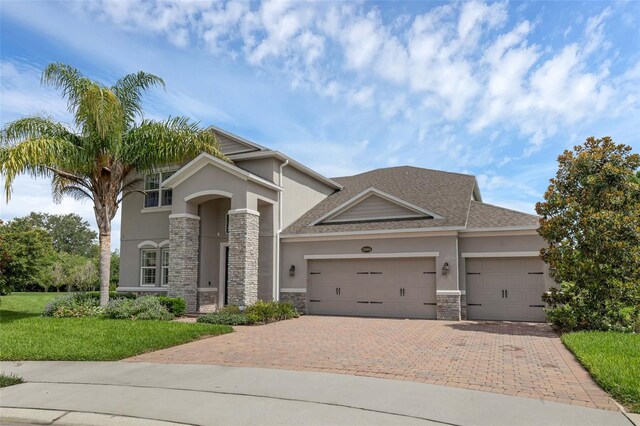 32004 Redtail Reserve Blvd, Sorrento, FL 32776 - view of front of house featuring stone siding, stucco siding, an attached garage, and decorative driveway