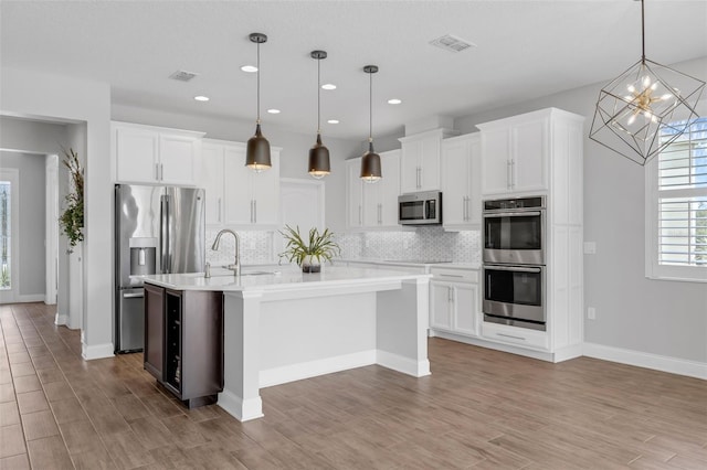 32004 Redtail Reserve Blvd, Sorrento, FL 32776 - kitchen featuring appliances with stainless steel finishes, backsplash, a kitchen island with sink, white cabinetry, and recessed lighting
