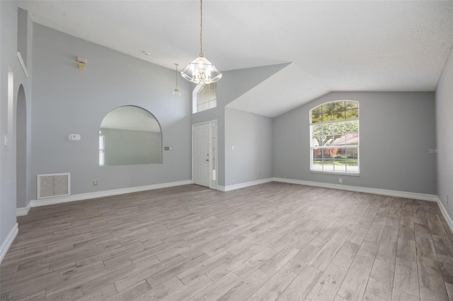 2767 Aragon Ter, Lake Mary, FL 32746 - unfurnished living room with lofted ceiling, light wood-style flooring, arched walkways, and a chandelier