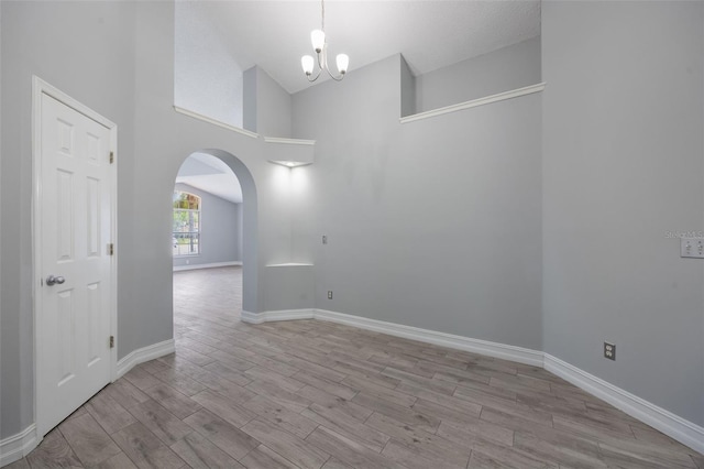 2767 Aragon Ter, Lake Mary, FL 32746 - empty room featuring arched walkways, wood finished floors, a chandelier, and high vaulted ceiling