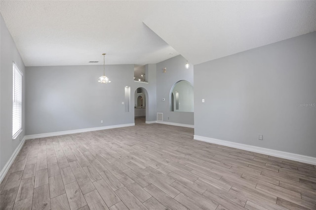 2767 Aragon Ter, Lake Mary, FL 32746 - unfurnished living room featuring lofted ceiling, light wood-type flooring, arched walkways, and a chandelier