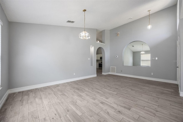 2767 Aragon Ter, Lake Mary, FL 32746 - spare room featuring high vaulted ceiling, light wood-style flooring, a chandelier, and arched walkways