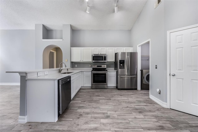 2767 Aragon Ter, Lake Mary, FL 32746 - kitchen with stainless steel appliances, arched walkways, a peninsula, light wood-style flooring, and a textured ceiling