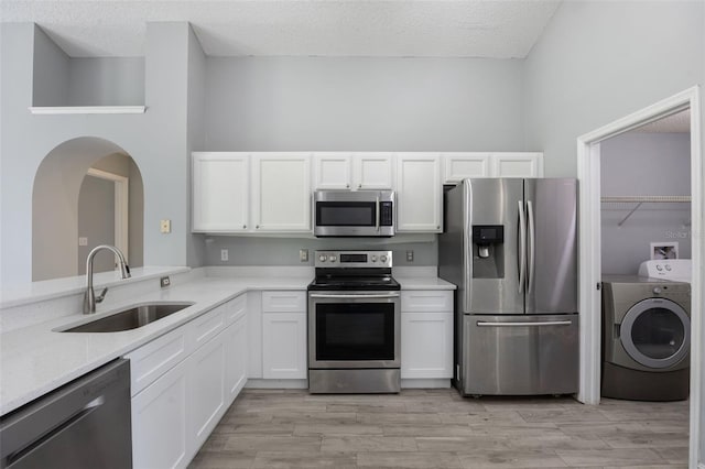 2767 Aragon Ter, Lake Mary, FL 32746 - kitchen with stainless steel appliances, washer / dryer, white cabinetry, a textured ceiling, and light wood finished floors