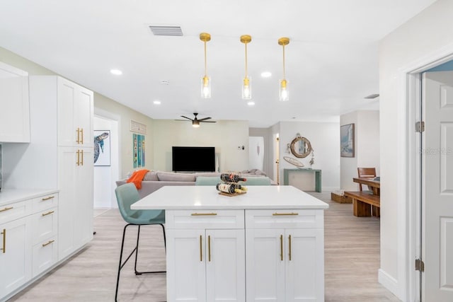 4311 123rd St W, Cortez, FL 34215 - kitchen with open floor plan, light countertops, a ceiling fan, white cabinets, and light wood-style floors