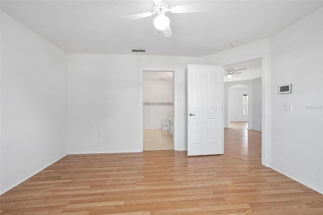710 Independence Dr, Orange City, FL 32763 - unfurnished bedroom with arched walkways, light wood-style floors, ensuite bath, and ceiling fan