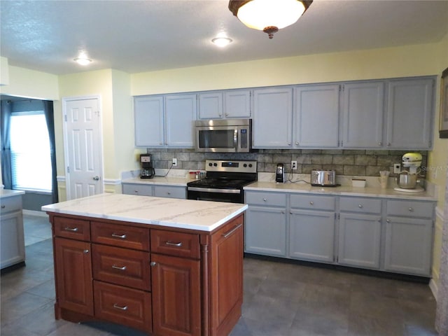 1420 Center St, Ocoee, FL 34761 - kitchen with stainless steel appliances, tasteful backsplash, gray cabinets, and a kitchen island