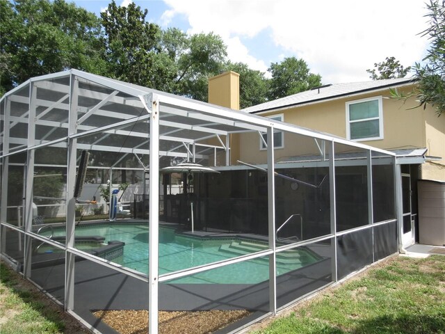 1420 Center St, Ocoee, FL 34761 - back of property featuring glass enclosure, stucco siding, a pool with connected hot tub, a patio, and a chimney
