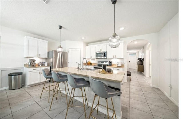 133 Hickory Course Cir, Ocala, FL 34472 - kitchen featuring stainless steel appliances, light tile patterned floors, arched walkways, white cabinets, and a breakfast bar