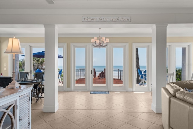 3309 Hill St, New Smyrna Beach, FL 32169 - living room with a water view, ornate columns, light tile patterned floors, a chandelier, and ornamental molding