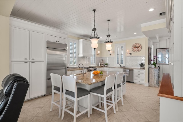 3309 Hill St, New Smyrna Beach, FL 32169 - kitchen featuring appliances with stainless steel finishes, premium range hood, light tile patterned floors, healthy amount of natural light, and crown molding