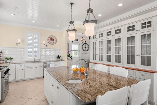 3309 Hill St, New Smyrna Beach, FL 32169 - kitchen featuring stainless steel appliances, a center island with sink, white cabinetry, stone counters, and tasteful backsplash