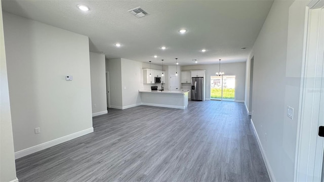 16252 SW 27th Terrace Rd, Ocala, FL 34473 - unfurnished living room with wood finished floors, a chandelier, recessed lighting, and a textured ceiling