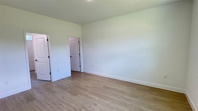 742 W Glenhaven Dr, Citrus Springs, FL 34434 - unfurnished bedroom with wood finished floors, a walk in closet, a closet, and a textured ceiling