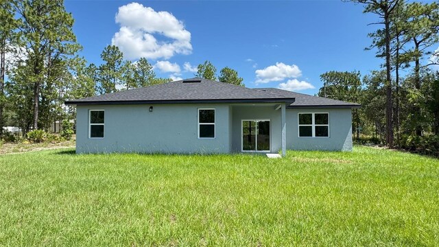 742 W Glenhaven Dr, Citrus Springs, FL 34434 - back of house featuring stucco siding, a yard, and roof with shingles