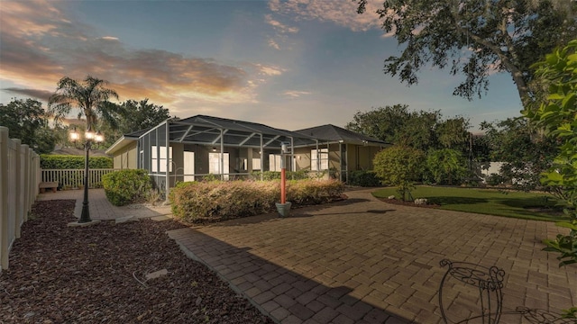1455 Royal Forest Loop, Lakeland, FL 33811 - back of house at dusk featuring glass enclosure and a patio area