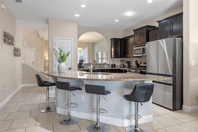 5172 Oakbourne Ave, Davenport, FL 33837 - kitchen with stainless steel appliances, arched walkways, a kitchen breakfast bar, light stone counters, and recessed lighting