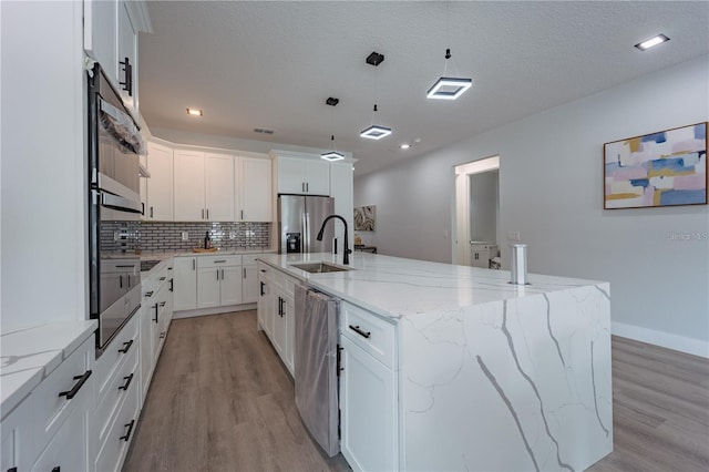 63 W 10th St, Apopka, FL 32703 - kitchen with light wood-style flooring, appliances with stainless steel finishes, tasteful backsplash, a spacious island, and pendant lighting
