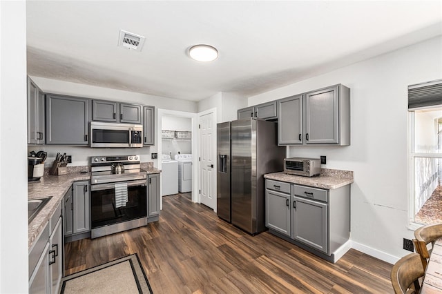 5430 NW 55th Pl, Ocala, FL 34482 - kitchen with stainless steel appliances, gray cabinets, independent washer and dryer, dark wood-style floors, and light stone counters