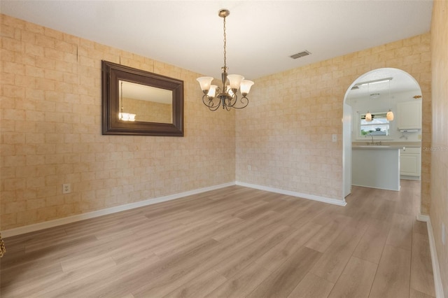 16243 Wilkinson Dr, Clermont, FL 34714 - empty room with light wood-type flooring, arched walkways, and a chandelier
