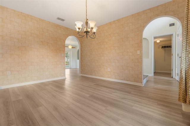 16243 Wilkinson Dr, Clermont, FL 34714 - unfurnished room with arched walkways, light wood-type flooring, a chandelier, and brick wall