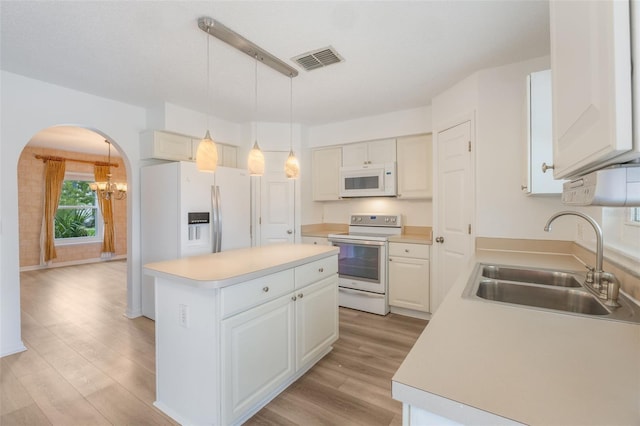 16243 Wilkinson Dr, Clermont, FL 34714 - kitchen featuring white appliances, arched walkways, a center island, light wood-style floors, and light countertops