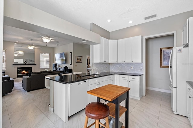 1225 Hollow Pine Dr, Oviedo, FL 32765 - kitchen featuring white appliances, a peninsula, white cabinets, a ceiling fan, and a tile fireplace