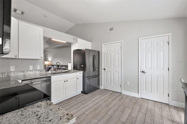 12419 Eryn Ct, Clermont, FL 34711 - kitchen featuring freestanding refrigerator, lofted ceiling, white cabinetry, light wood finished floors, and light stone counters