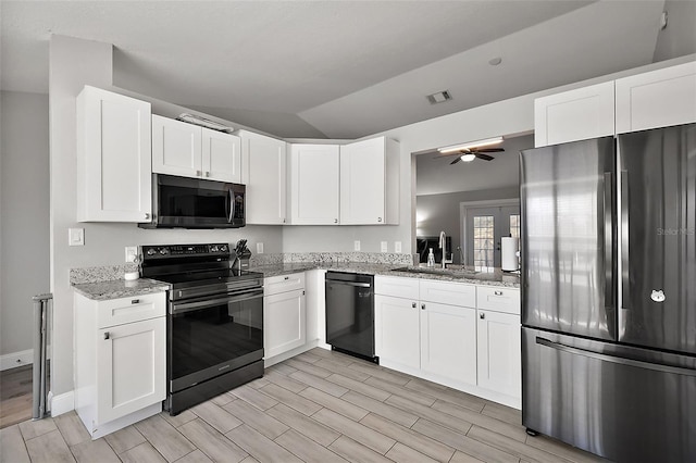12419 Eryn Ct, Clermont, FL 34711 - kitchen with black appliances, wood finish floors, light stone countertops, white cabinets, and vaulted ceiling