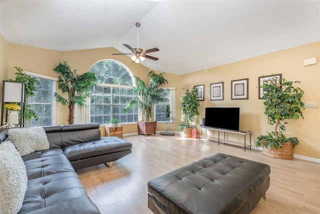 living area with ceiling fan, wood finished floors, and vaulted ceiling