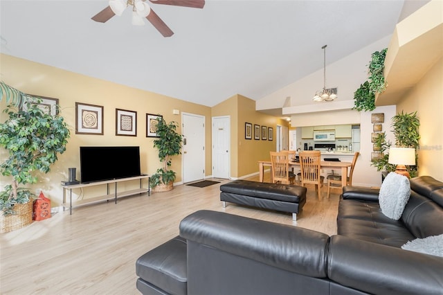 living area with wood finished floors, ceiling fan, high vaulted ceiling, and a chandelier