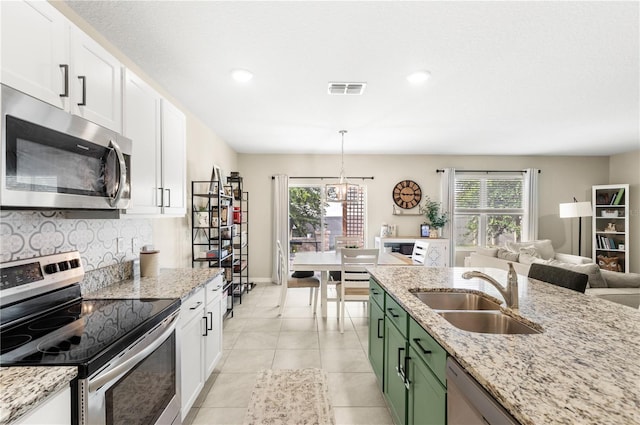 9024 Alba Ln, Kissimmee, FL 34747 - kitchen with stainless steel appliances, green cabinetry, decorative backsplash, white cabinets, and light stone counters