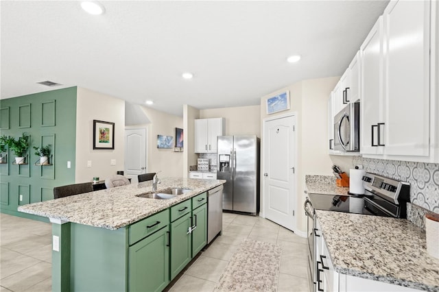 9024 Alba Ln, Kissimmee, FL 34747 - kitchen featuring stainless steel appliances, green cabinets, a center island with sink, white cabinetry, and backsplash