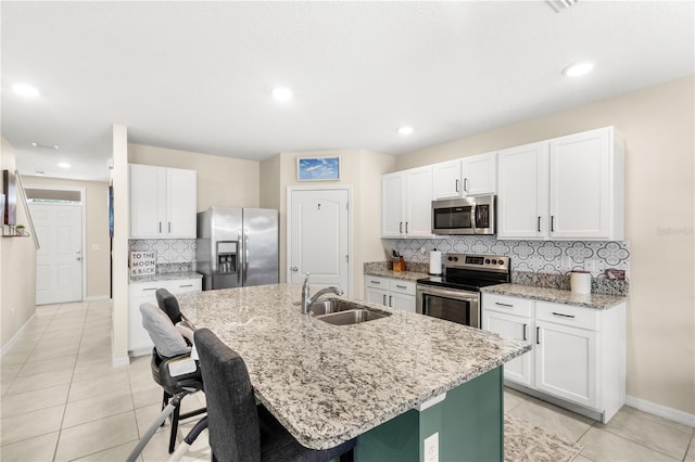 9024 Alba Ln, Kissimmee, FL 34747 - kitchen with appliances with stainless steel finishes, decorative backsplash, a center island with sink, light tile patterned flooring, and light stone countertops
