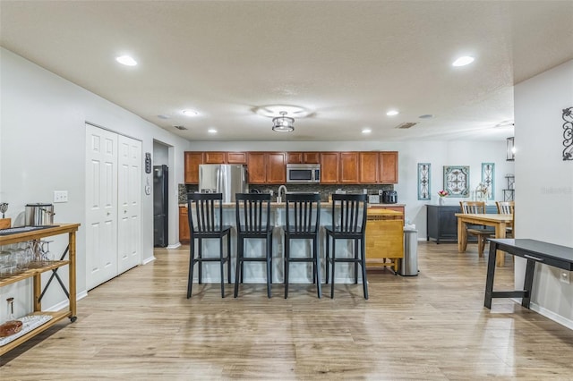 2032 Wavyleaf Ct, Apopka, FL 32712 - kitchen featuring appliances with stainless steel finishes, a breakfast bar, light wood-style floors, recessed lighting, and brown cabinets