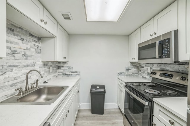936 Lake Destiny Rd Unit G, Altamonte Springs, FL 32714 - kitchen with stainless steel appliances, decorative backsplash, light countertops, light wood-style floors, and white cabinetry