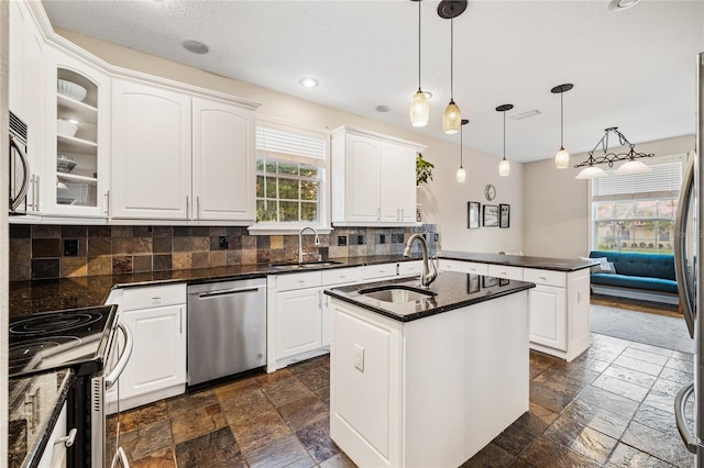 1443 Stone Trl, Enterprise, FL 32725 - kitchen with stainless steel appliances, stone tile flooring, a peninsula, backsplash, and a center island with sink