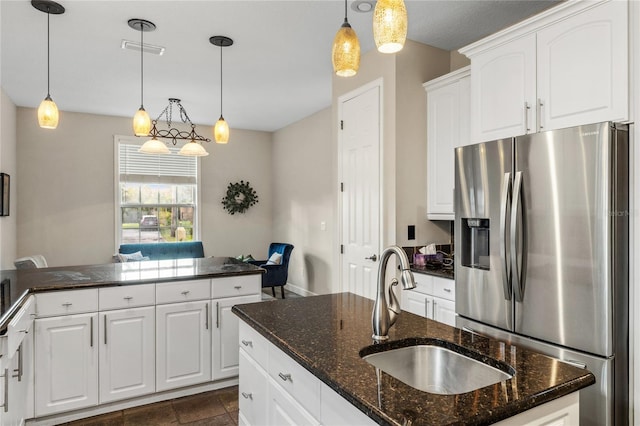 1443 Stone Trl, Enterprise, FL 32725 - kitchen featuring stainless steel refrigerator with ice dispenser, white cabinets, hanging light fixtures, dark stone countertops, and a kitchen island with sink