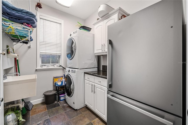 1443 Stone Trl, Enterprise, FL 32725 - laundry area with stacked washer and clothes dryer, cabinet space, and stone tile flooring