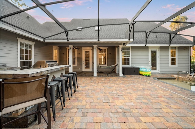 1443 Stone Trl, Enterprise, FL 32725 - back of property at dusk with glass enclosure, a shingled roof, a patio, and ceiling fan