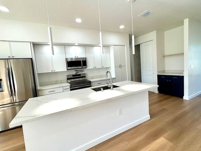 2634 De Groodt Rd SW, Palm Bay, FL 32908 - kitchen with stainless steel appliances, light wood finished floors, a textured ceiling, white cabinets, and recessed lighting