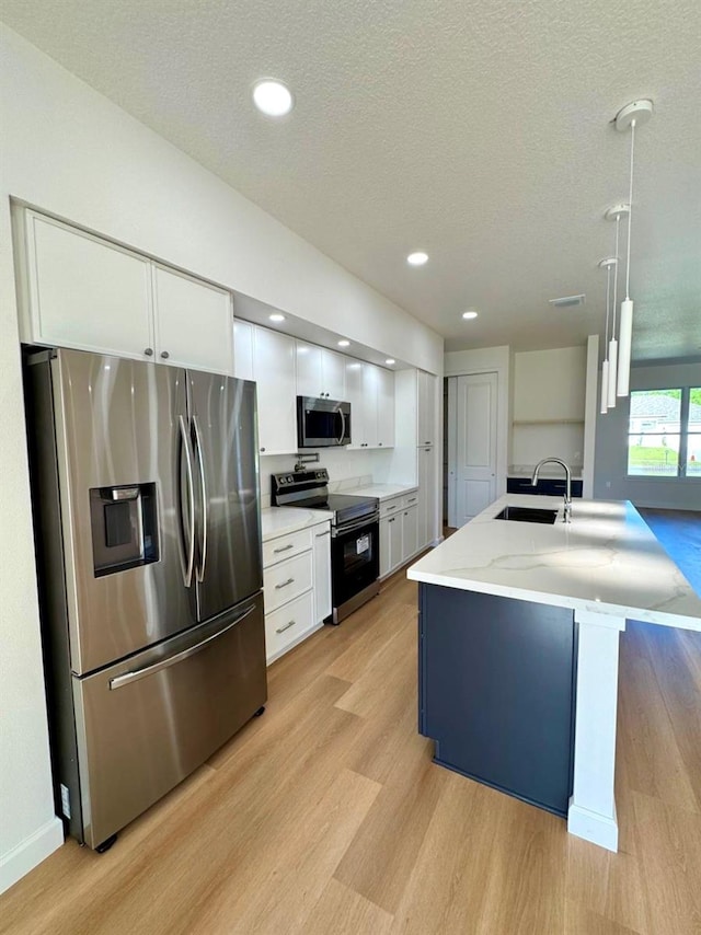 2634 De Groodt Rd SW, Palm Bay, FL 32908 - kitchen with stainless steel appliances, light wood-style floors, white cabinetry, a textured ceiling, and light stone counters