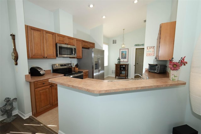 2362 Prairie Dunes, Clermont, FL 34711 - kitchen with appliances with stainless steel finishes, vaulted ceiling, brown cabinetry, light countertops, and a peninsula