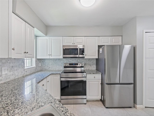 750 Olympic Cir Unit D1, Ocoee, FL 34761 - kitchen with appliances with stainless steel finishes, white cabinetry, light stone counters, tasteful backsplash, and light tile patterned floors