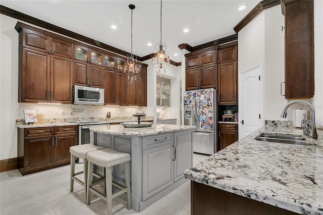 2388 Baronsmede Ct, Winter Garden, FL 34787 - kitchen featuring appliances with stainless steel finishes, a kitchen island, decorative backsplash, ornamental molding, and a kitchen bar
