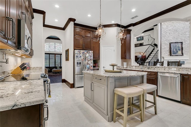 2388 Baronsmede Ct, Winter Garden, FL 34787 - kitchen featuring appliances with stainless steel finishes, ornamental molding, arched walkways, a kitchen island, and dark brown cabinetry