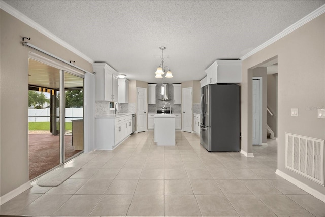 2725 White Magnolia Loop, Clermont, FL 34711 - kitchen with appliances with stainless steel finishes, tasteful backsplash, wall chimney range hood, a textured ceiling, and a chandelier